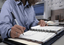 woman writing notes in daily planner